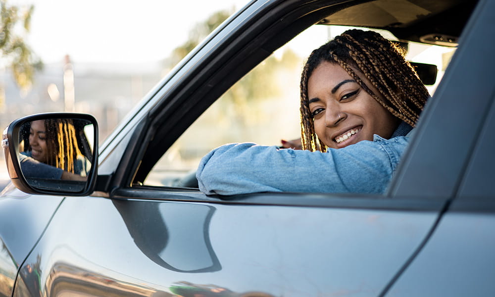 A woman smiling looking out a car window