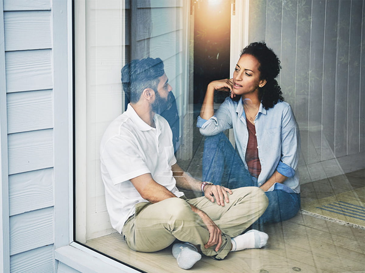 A couple sitting on the floor having a discussion