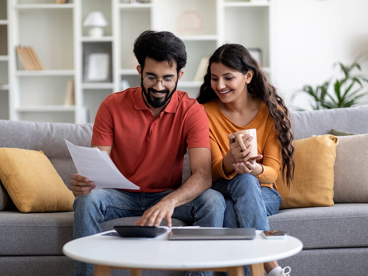 A couple sitting on a couch looking at paperwork