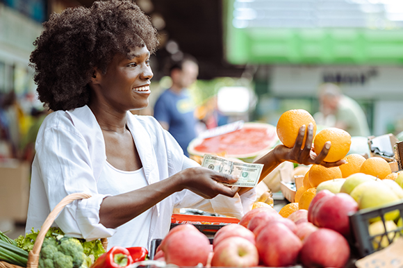 A woman paying for fruit with cash